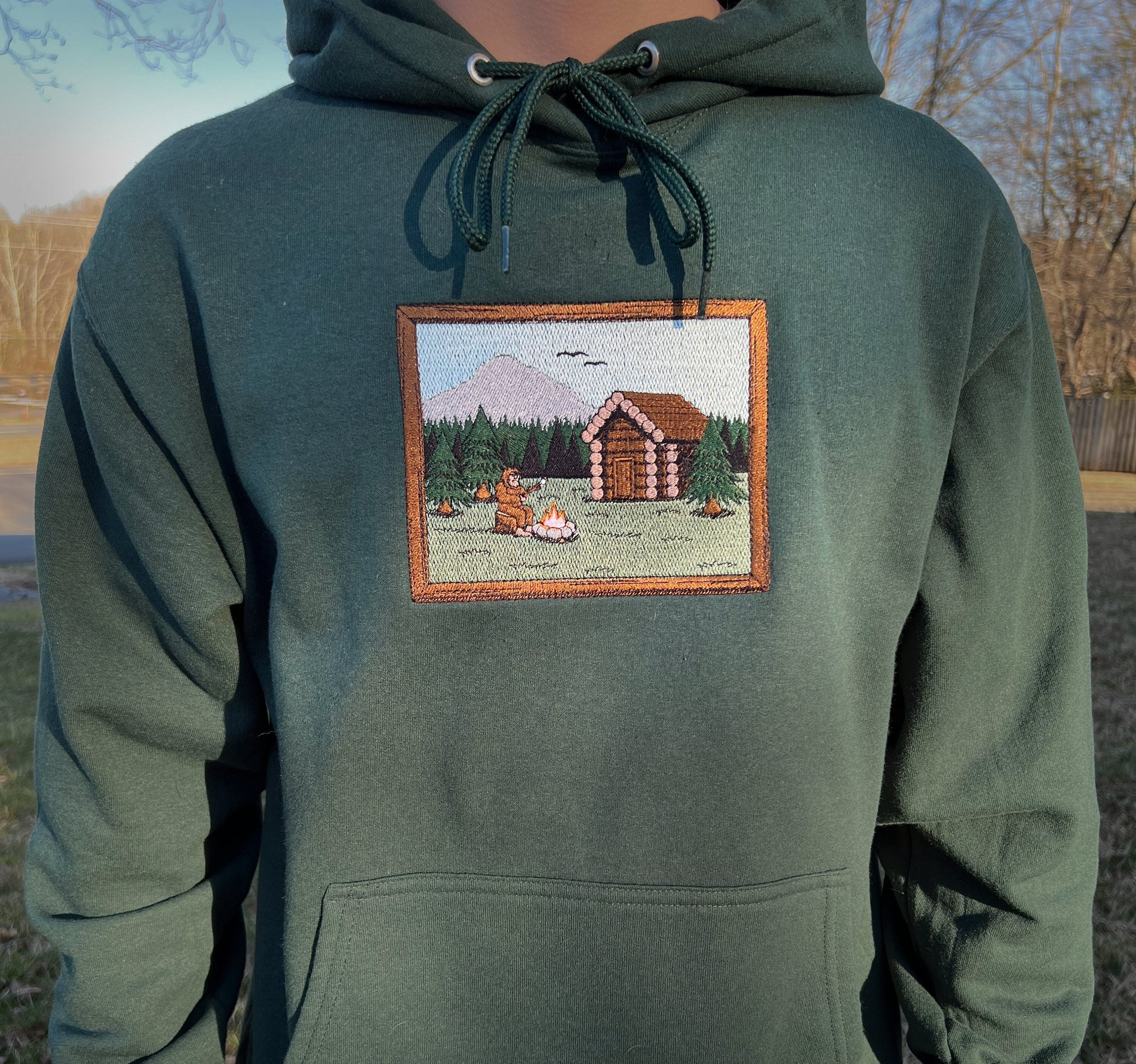 Sasquatch Log Cabin Scene Embroidered Hoodie Sweatshirt Unisex Camping Forest Mountains Long Sleeve Outdoors Personalized Multiple Colors
