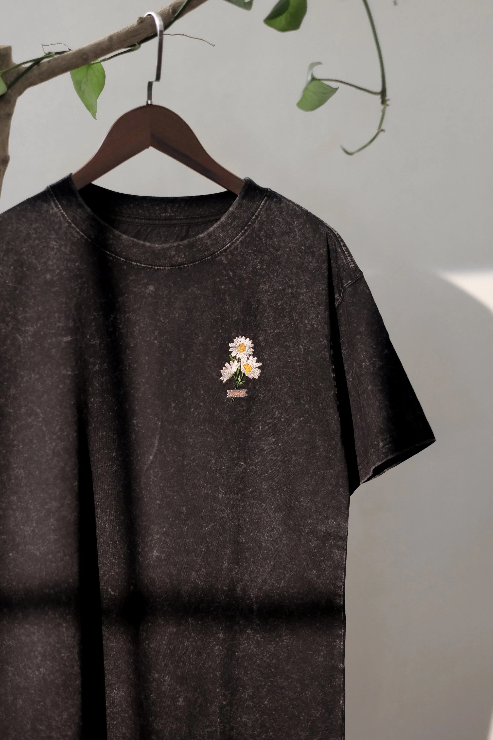 Black t-shirt embroidered with daisy flowers. Oversize shirt form. Streetwear style