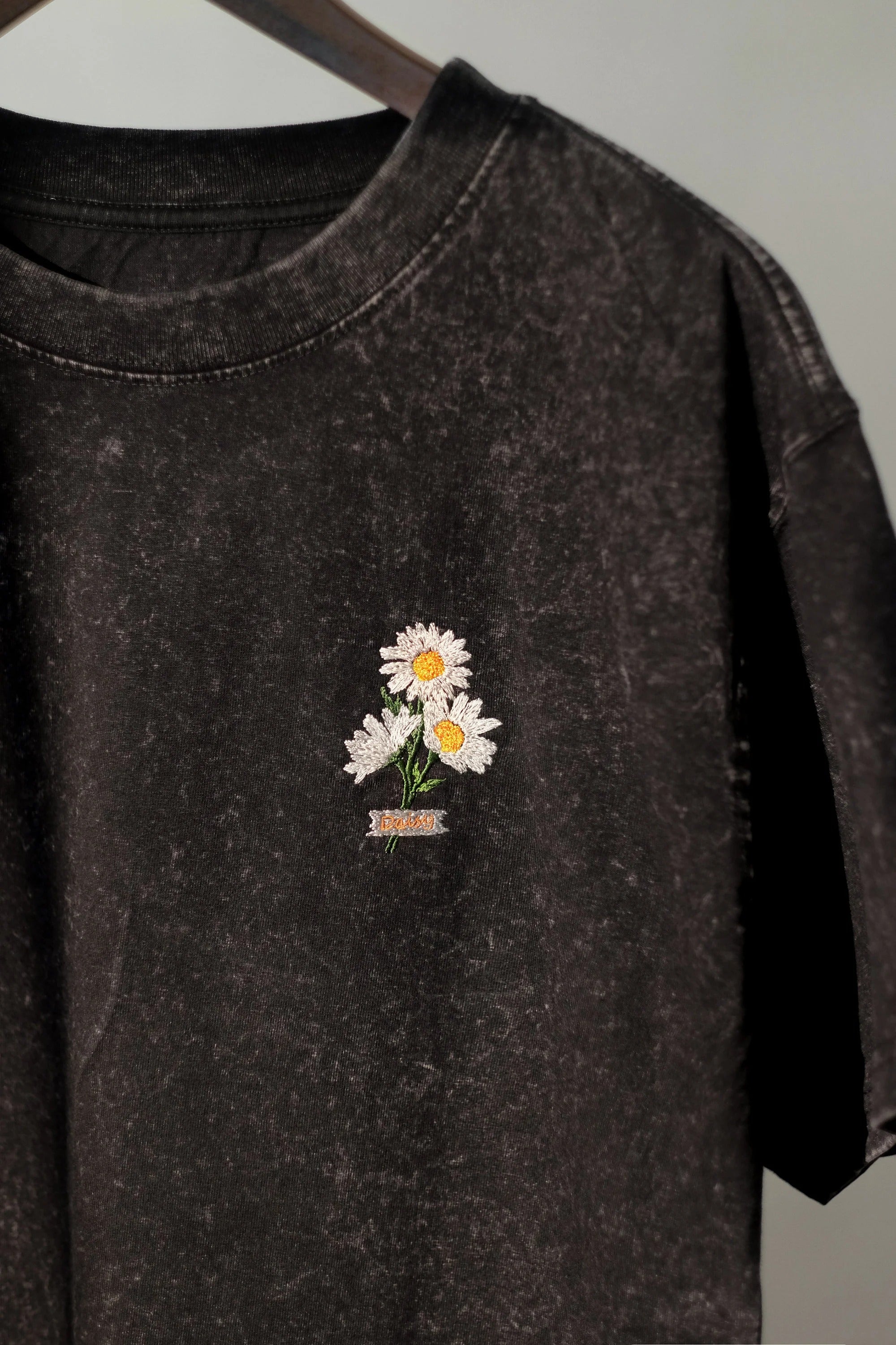 Black t-shirt embroidered with daisy flowers. Oversize shirt form. Streetwear style